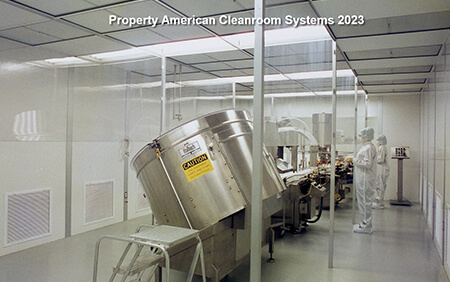 Pharmaceutical cleanroom interior, stainless steel mixers, personnel in bunny suits